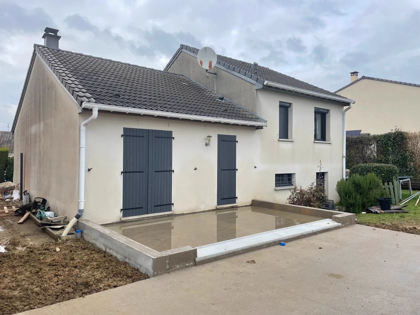 Pavillon et dalle de béton fraîchement coulée contre le pignon, avant construction de l'extension