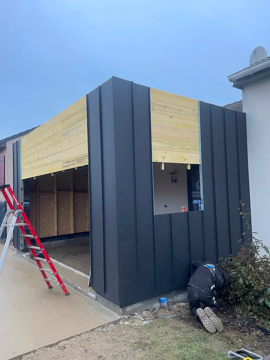 Bardage aluminium à joint debout en cours de pose sur une extension, ossature encore apparente au-dessus