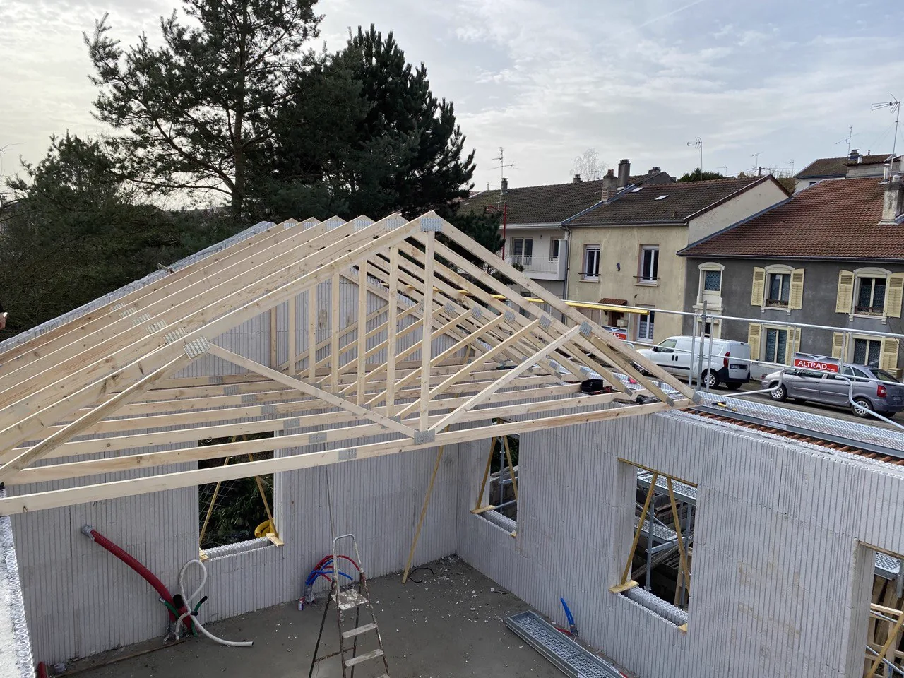 Charpente à fermettes neuves posée sur des murs en cours de construction