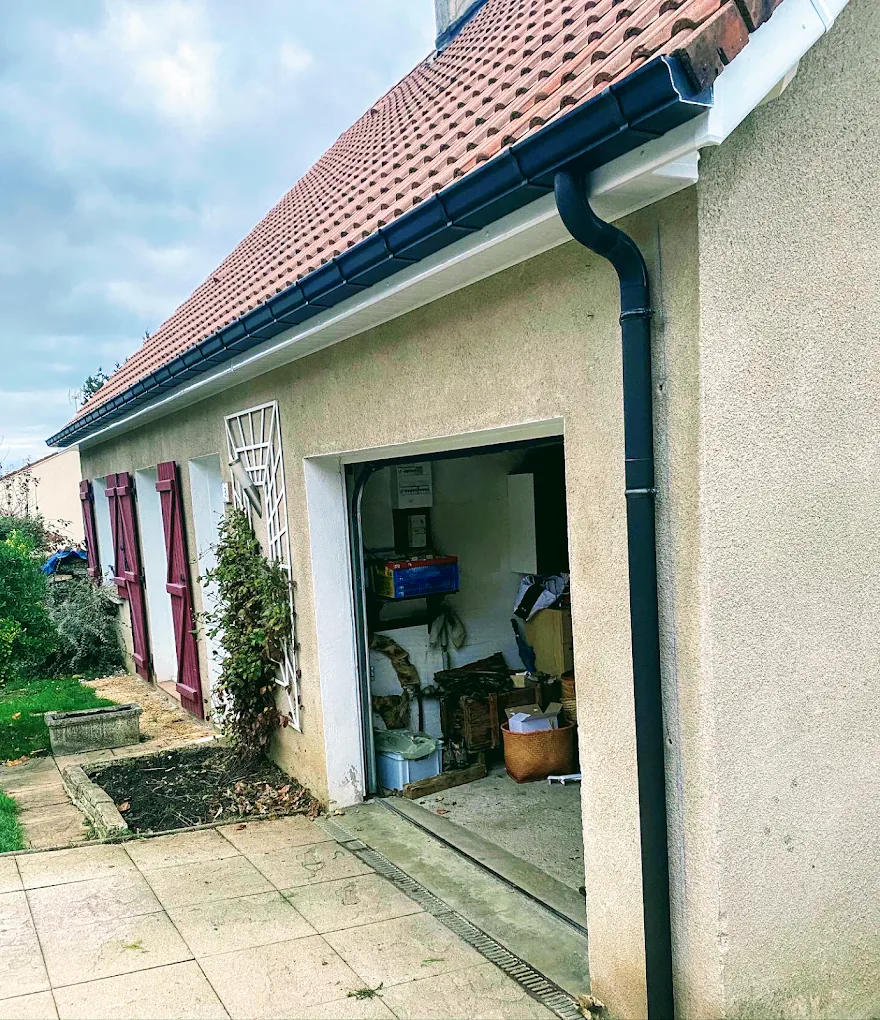 Gouttière et descente en zinc le long d'un mur enduit, sur une maison de bourg