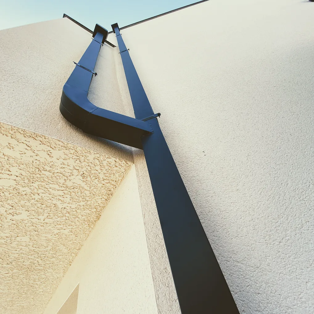 Naissance et descente en zinc anthracite sur un mur enduit blanc