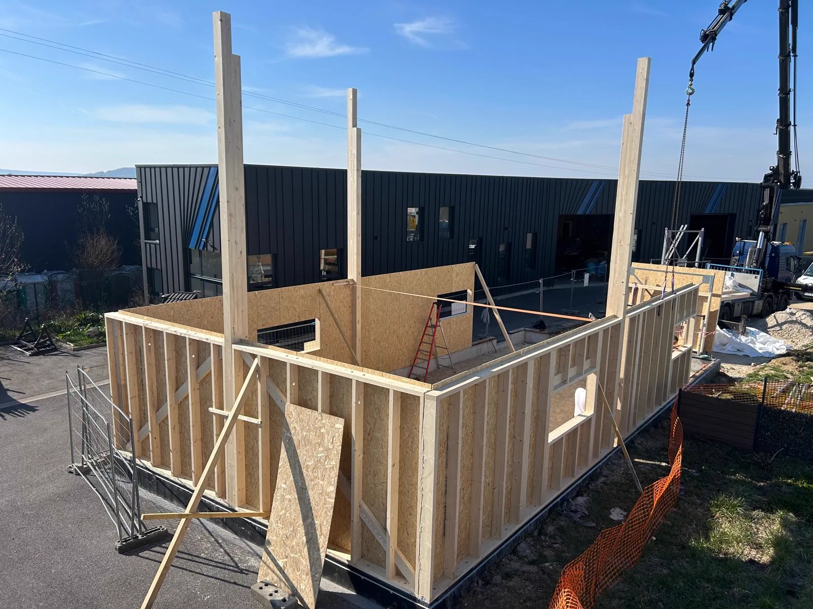 Un mur en ossature bois monté dans la cour de l'atelier LMB à Ville-en-Vermois, devant le bâtiment en bardage zinc